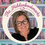 The reader behind The Hidden Bookmarks, smiling in front of her bookshelves
